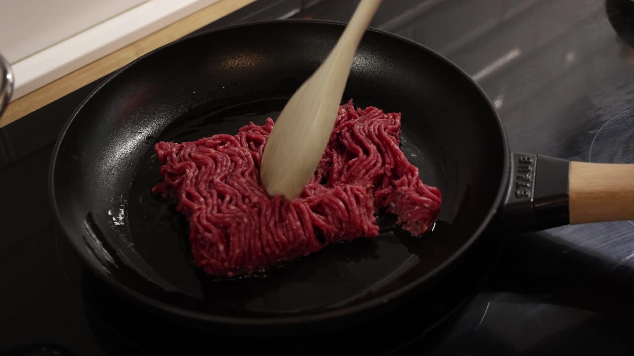 Raw ground beef placed into frying pan on stovetop ready to start cooking process