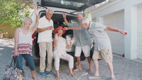 Portrait-Of-Excited-Senior-Friends-Loading-Luggage-Into-Trunk-Of-Car-About-To-Leave-For-Vacation