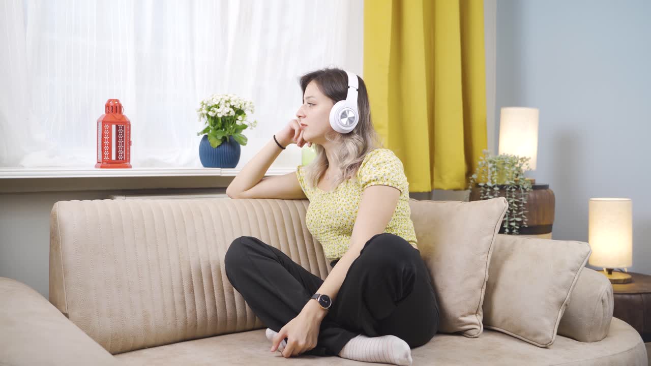 불행한 젊은 여성이 헤드폰으로 음악을 듣고 있습니다.