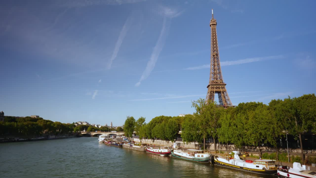 Riverboats pass and turn around carrying tourists on scenic tours with views of the iconic Eiffel Tower. Time lapse daylight view of Paris, France from the river, the Eiffel Tower in the background.