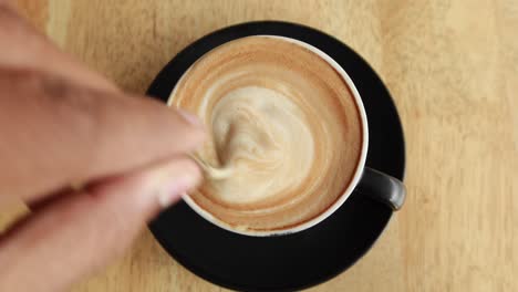 person hand stirring coffee with spoon