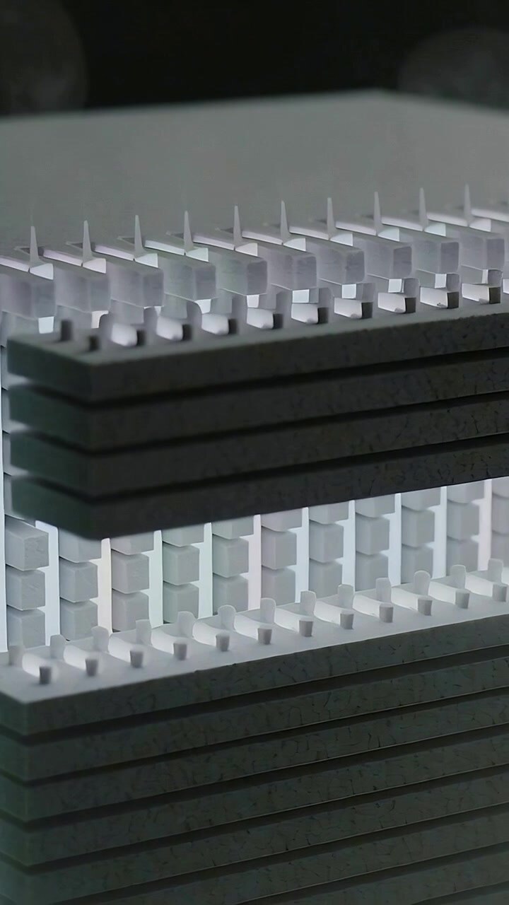 Vertical video: Light brightening, dark block sliding across layered slabs in studio