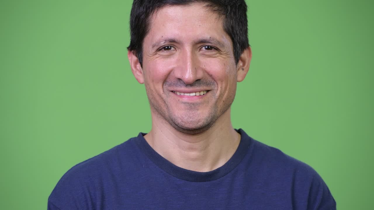 Happy Hispanic man smiling against green background
