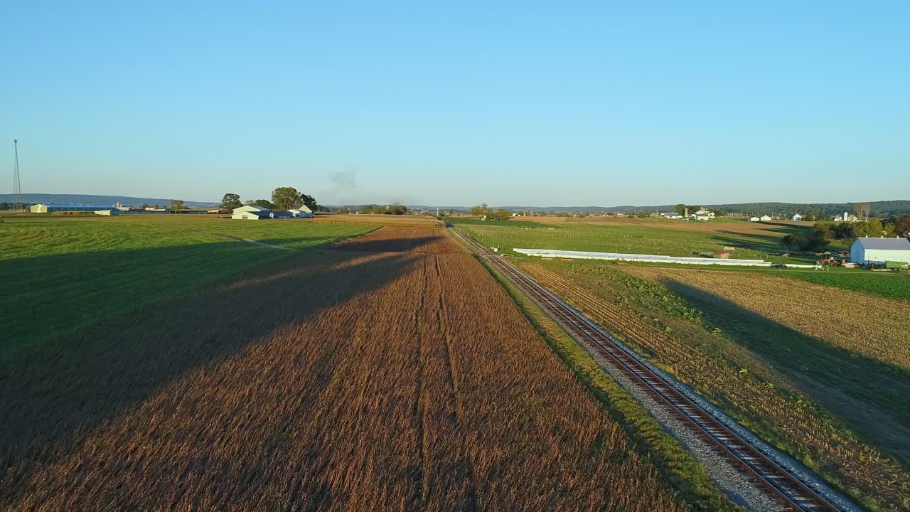 A Drone View of Crops Waiting to be Harvested as a Stream Passenger Train Approaches During the Golden Hour on a Fall Day