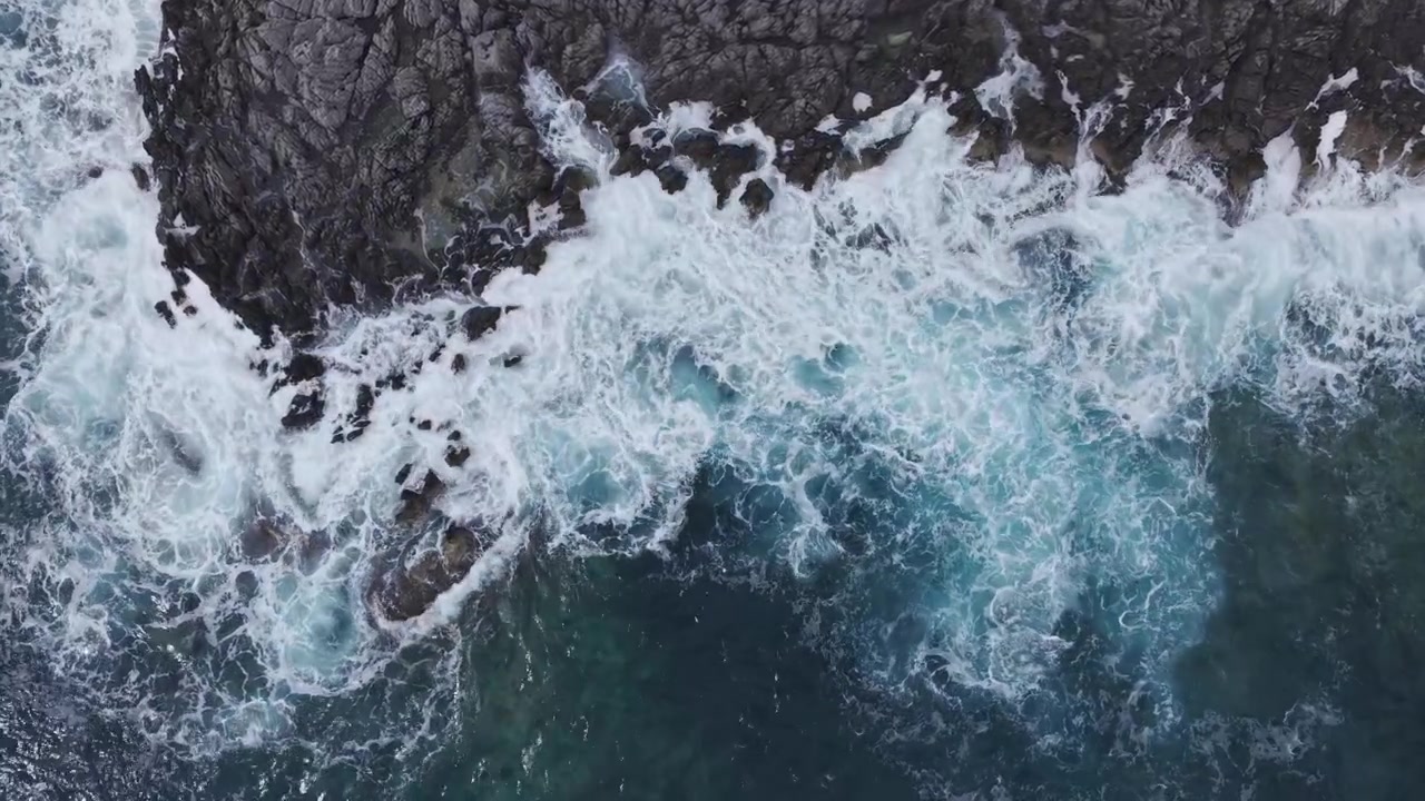 Vista aerea di onde oceaniche che si infrangono sulle rocce costiere.
