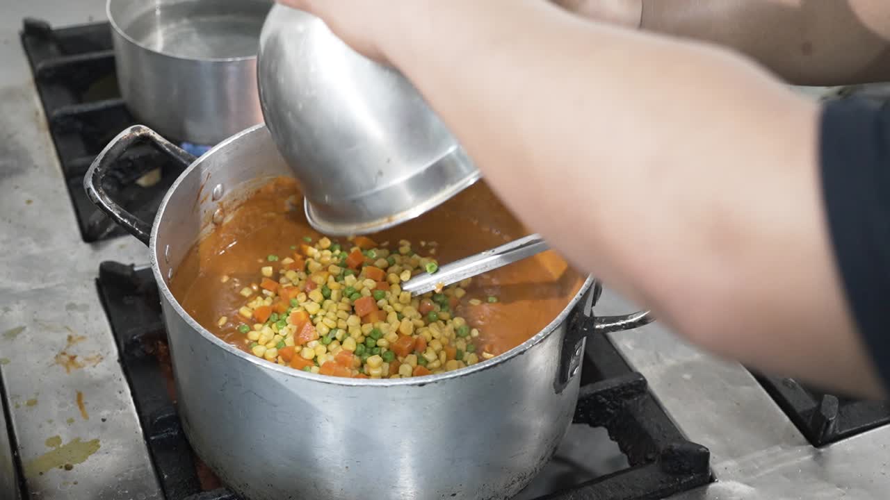 añadir verduras mezcladas en cubitos a la sopa hirviendo en una olla grande en una estufa, proceso de cocción