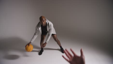 studio shot of male basketball player dribbling and passing ball to team mate 1