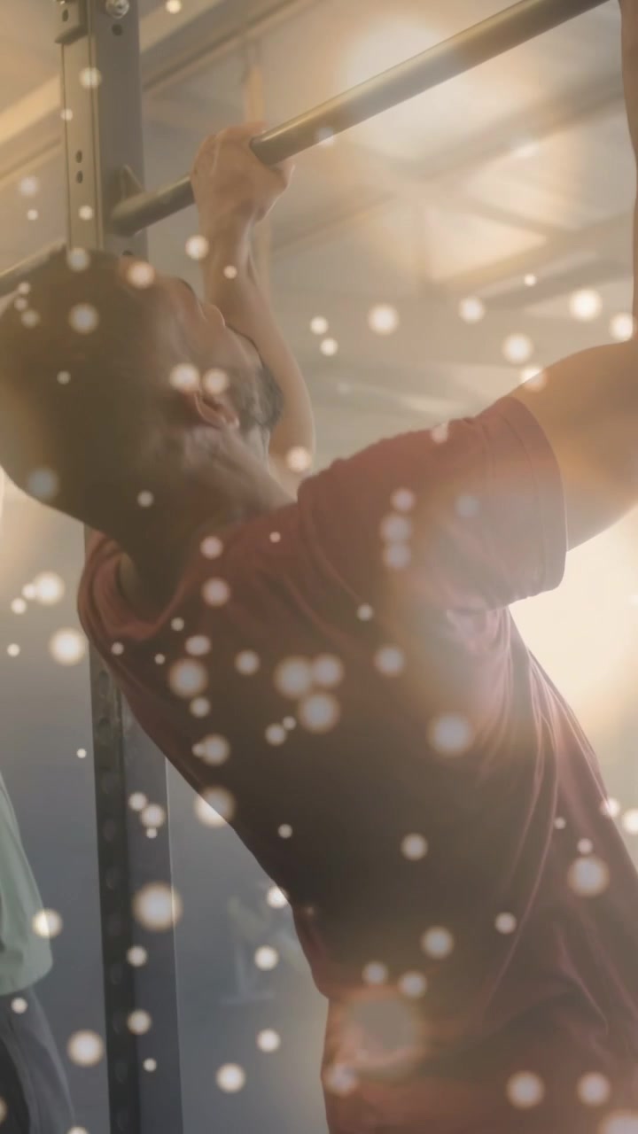 Vídeo vertical: Homem de camisa bordô segurando a barra, fazendo flexões, com um efeito bokeh que realça o fitness.