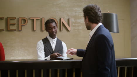 Un-Joven-Recibiendo-La-Llave-De-Su-Habitación-En-El-Hotel.