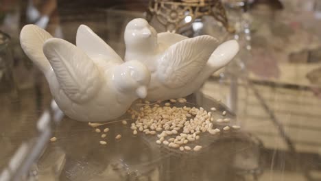 ceramic decoration of two white doves eating seeds on reflective table