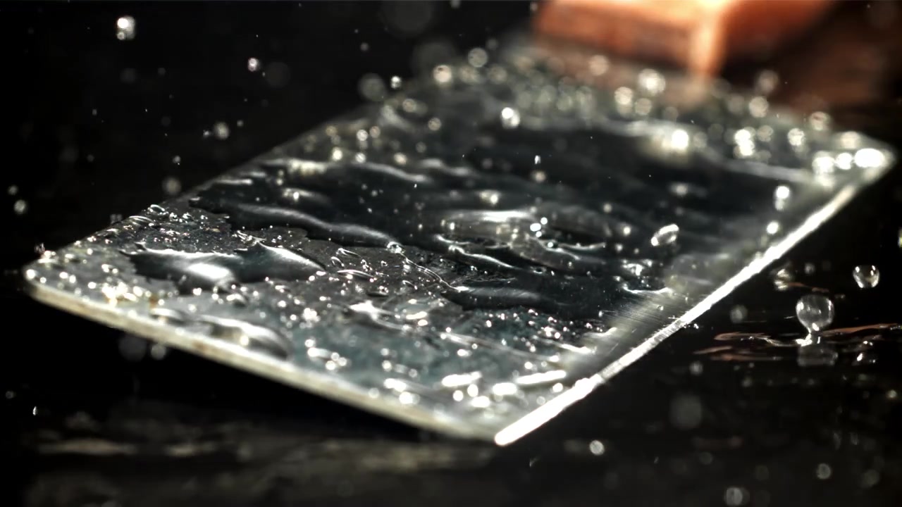 Slow Motion Water Drops Splashing on a Metallic Surface