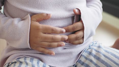 a young child holds their stomach as if in pain.