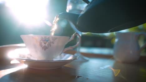 Té-Vertido-En-Una-Taza-De-Té-Antigua-Con-Luz-De-Fondo-Mágica,-Cámara-Lenta