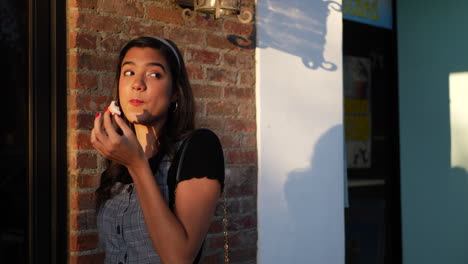 una hermosa joven comiendo un delicioso pastel dulce afuera de una panadería de comida callejera en cámara lenta