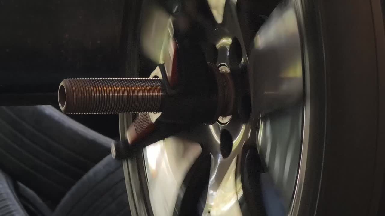 自動車工場で、バランス調整機の上で回転する自動車のホイールとタイヤ