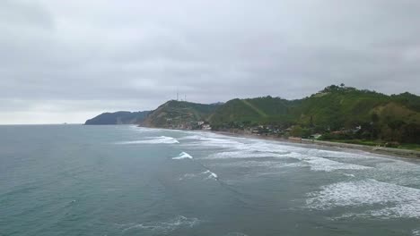 Aerial-drone-view-of-waves-splashing-at-the-shore-of-Olon-beach-in-Ecuador