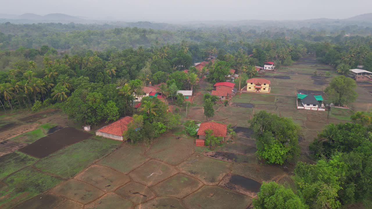A mesmerizing 4K drone view of Avalegaon, Kudal village in Konkan, Maharashtra, India, showcasing its charm with traditional houses, lush green trees, vast fields and mountains under a pink sky
