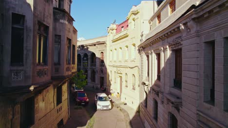 Boom-up-of-the-old-European-architecture-of-the-Concha-y-Toro-neighborhood-with-a-white-car-passing-through-cobblestone-streets,-Santiago,-Chile