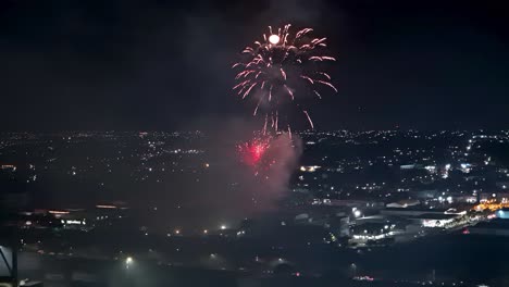 Aerial-fireworks-launch-high-into-air-as-full-moon-illuminates-clouds-and-reflects-on-water,-Curacao