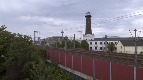 a commuter train on the way to aachen in cologne ehrenfeld on a cloudy day in front of the panorama scenery of cologne ehrenfeld with the tv tower in the background