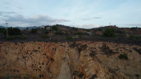 Push-out-shot-of-people-on-the-edge-of-a-rocky-cliff-taken-during-Blue-hour-in-Candado-Beach,-Spain