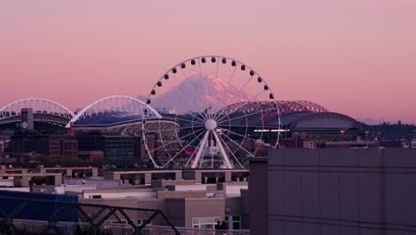 seattle's ferris wheel slowly moving with mount rainier framed in the backdrop.