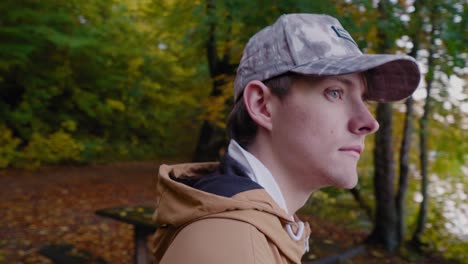 young scandinavian guy looks around and walks to explore the gyllebo lake in fall, österlen, skåne, sweden - close up pan to right