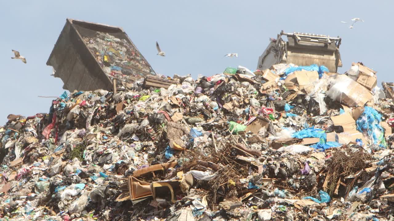 los camiones de basura tiran la basura en una enorme pila