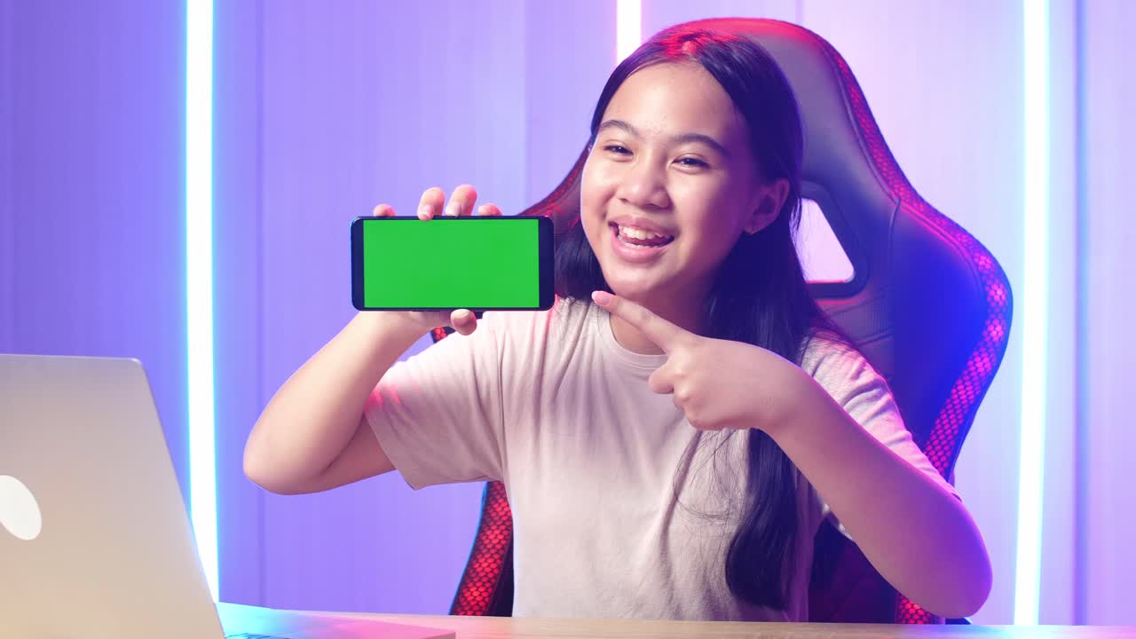 Asian Kid Girl Holding Mobile Phone With Mock Up Green Screen While Live Stream