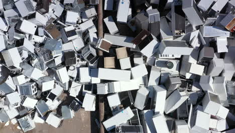 aerial ascent above massive pile of white discarded appliances