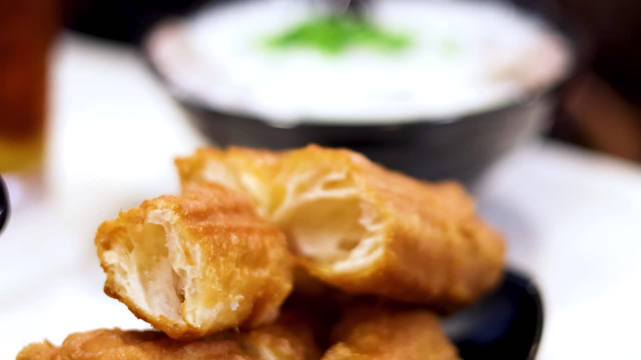 Close-up of hands tearing apart crispy fried dough sticks, revealing their airy interior.