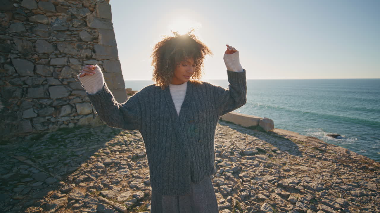 Beach woman admiring landscape enjoying sun closeup. Curly hair traveler resting