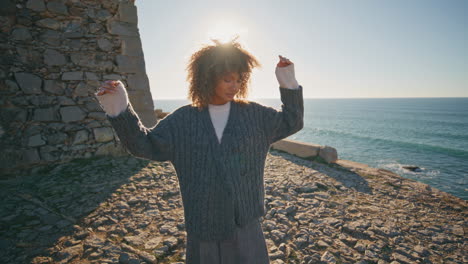 Beach woman admiring landscape enjoying sun closeup. Curly hair traveler resting