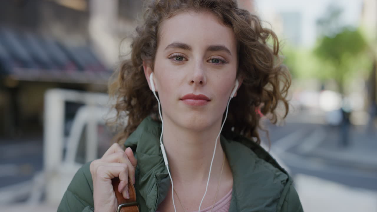 retrato de una mujer joven atractiva sonriendo tranquila mirando a la cámara disfrutando escuchando música con auriculares en la calle de la ciudad hermosa mujer caucásica estilo de vida urbano