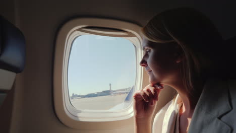 a young woman looks out the window of the plane which begins to accelerate along the runway start of