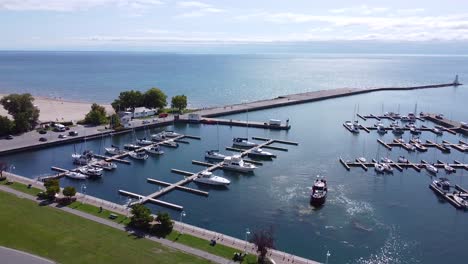 marina waterfront with sail boats docked, pier, lighthouse and sandy beach with clear blue water