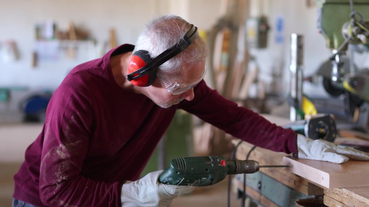 Senior carpenter using a power drill in his workshop