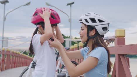 mother helping daughter with bike helmet