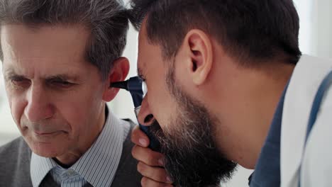 handheld video shows of doctor examining ear of senior man