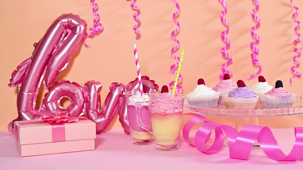 발렌타인 데이를 위해 풍선, 리본, 달한 디저트 컵 케이크로 장식하는 테이블.