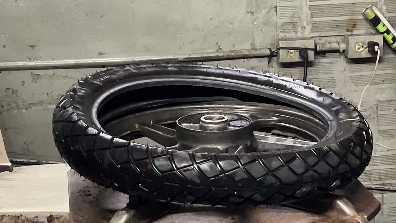 mecánico arreglando un neumático de motocicleta en su taller_servicio hombre_rueda