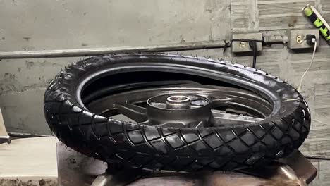 mechanic fixing a motorcycle tire in his workshop_service man_wheel