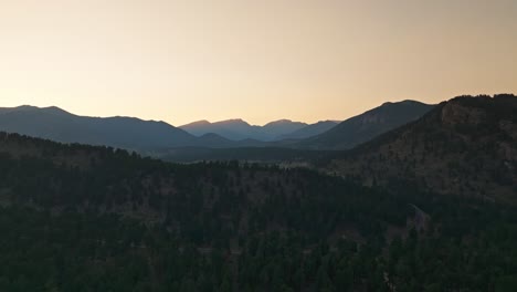 aerial view of a forested mountain range at dusk, with fading light over the distant peaks