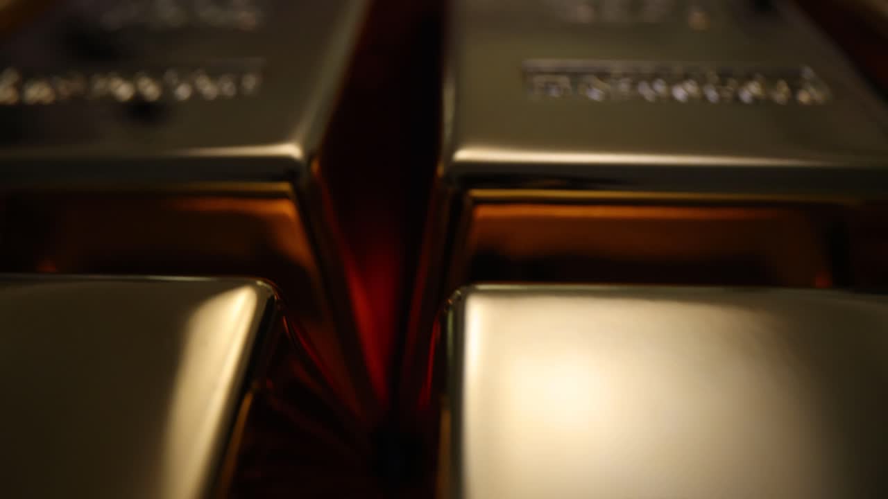 Close-up view of shiny gold bars, some showing 'GOLD' and 'NET WT' inscriptions