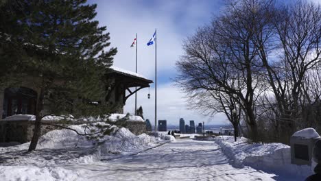 2 people walk towards building with flags of montreal and quebec flapping in the air