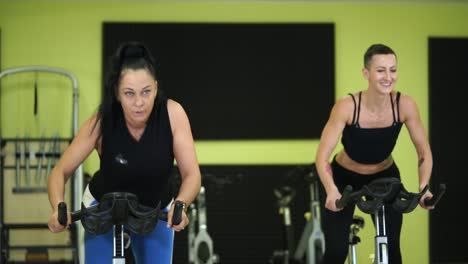two women exercising on spinning bikes
