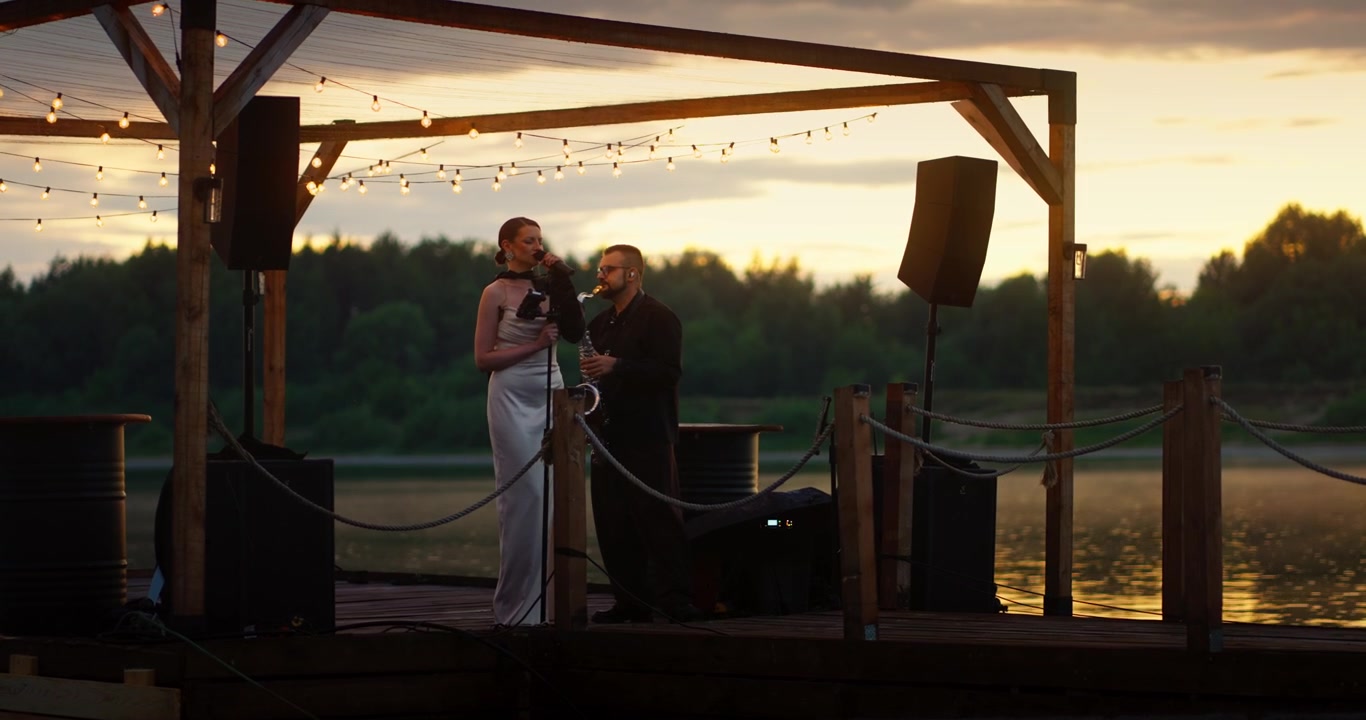 Duo Performing Music on a Wooden Pier at Sunset