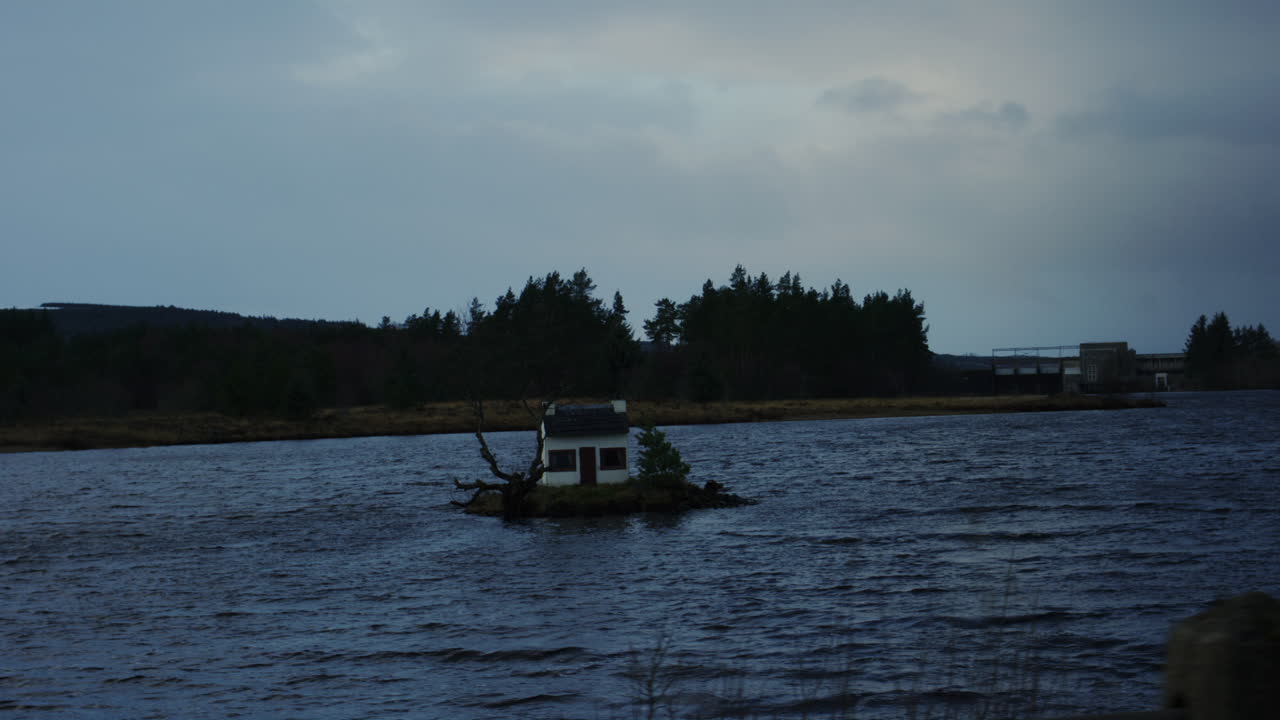 Small crannog home in open water at dusk near forested island silhouettes