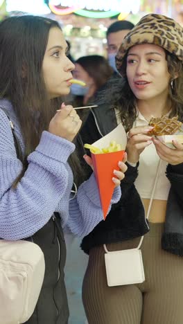 two young women enjoying street food at a night market