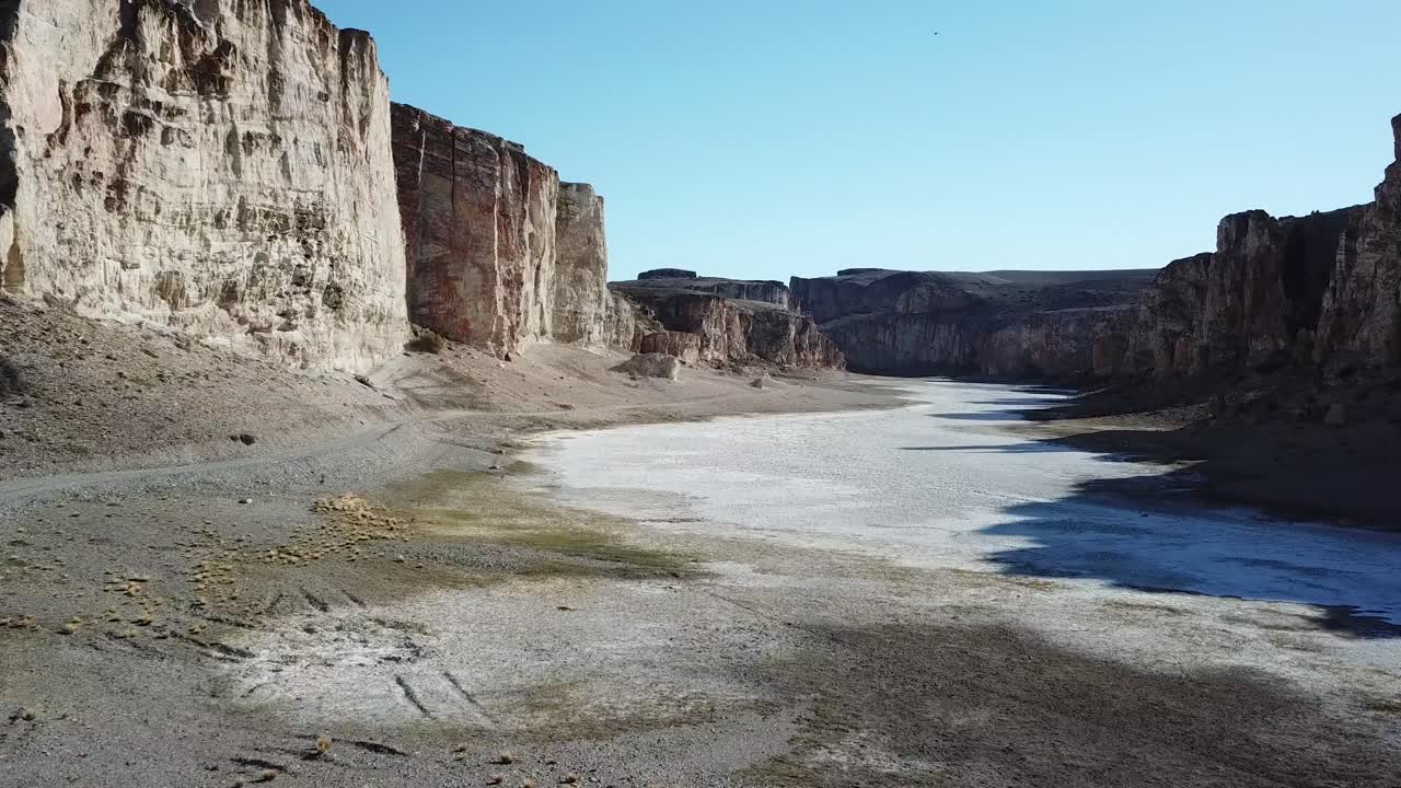 Salt Flat Canyon and Desert Road Under Steep Dry Cliffs, Pull Back Drone Aerial View, Patagonia, Argentina